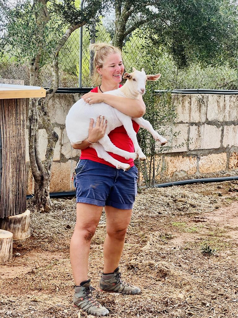 Unsere Mitarbeiterin Steffi hat eine unserer zahmen Ziegen auf dem Arm